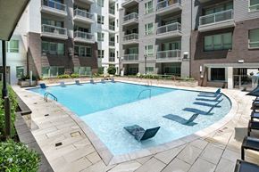 Atlanta apartment for rent - A large outdoor swimming pool surrounded by lounge chairs and buildings.