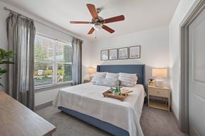 Swampscott apartment for rent - Bedroom with a wood-blade ceiling fan, an upholstered headboard, carpet and a window with blinds and curtains.