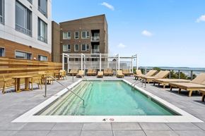Revere apartment for rent - A large outdoor swimming pool with loungers and a white fence.