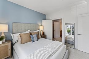 Marshfield townhouse for rent - Second view of a bedroom with a blue accent wall, upholstered bed, mirror, and doorway.