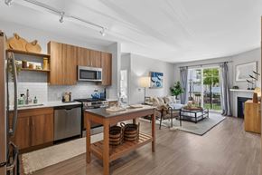 Marshfield townhouse for rent - Open apartment kitchen and living room with stainless steel appliances, island, sofa, and patio door.
