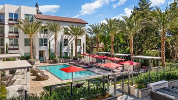 Sun-splashed pool with lounge chairs and shaded seating