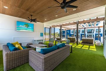 Jacksonville apartment for rent - A living room with a ceiling fan and a painting of a beach scene on the wall.