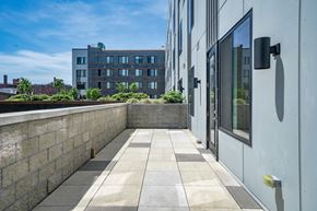 Bayonne apartment for rent - A modern building with a stone wall and glass doors.