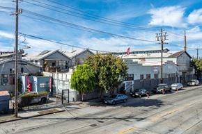 Oakland apartment for rent - A street view with cars parked on the side of the road and a building with a red flag on top in the background.