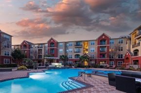 Houston apartment for rent - a swimming pool at dusk with an apartment building in the background