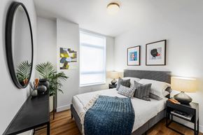 Vancouver apartment for rent - A bedroom with a bed, nightstand, and a mirror on the wall.