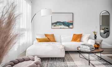 Vancouver apartment for rent - A modern living room with a white sofa, a grey rug, and a painting on the wall.