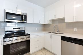 Calgary apartment for rent - A modern kitchen with white cabinets and black appliances.