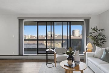 Edmonton apartment for rent - A modern living room with a view of the cityscape outside the large window.