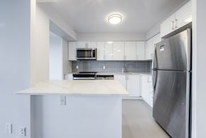 Burlington apartment for rent - A modern kitchen with a stainless steel refrigerator and white cabinets.