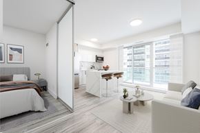 Toronto apartment for rent - A modern bedroom with a large bed and a separate living area with a couch.