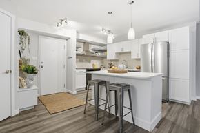 Edmonton apartment for rent - A kitchen with white cabinets and a white island with a refrigerator on the right side.