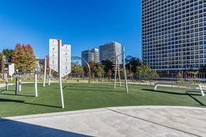 Toronto apartment for rent - A playground with a climbing frame and a slide in the foreground with a cityscape in the background.