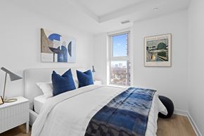Ottawa apartment for rent - A bedroom with a white bed and a blue and white patterned blanket.