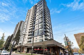 Vancouver apartment for rent - A tall building with a lot of windows is in the middle of a street with cars and trees.