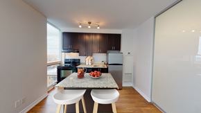 Toronto apartment for rent - A kitchen with a table and chairs in the foreground and a refrigerator, microwave, and oven in the background.