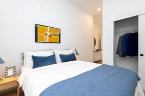 Montreal apartment for rent - A bedroom with a white bed and a blue blanket.