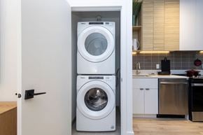 Montreal apartment for rent - A white front loading washing machine is in a cabinet in a kitchen.