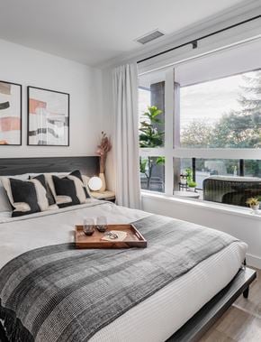 Vancouver apartment for rent - A bedroom with a large bed and a tray with glasses and a pair of sunglasses on it.