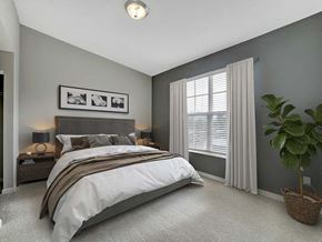 Columbus apartment for rent - A bedroom with a large bed and a potted plant.