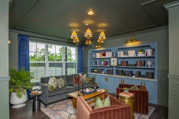 Columbus apartment for rent - A living room with a grey couch, a red armchair, a wooden coffee table, and a bookshelf with books and decorative items.
