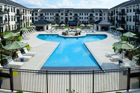Columbus apartment for rent - A large swimming pool surrounded by lounge chairs and umbrellas in a resort-like setting.
