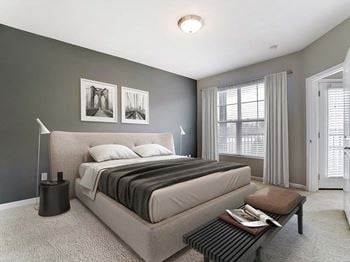 A bedroom with a bed and a table in front of a window