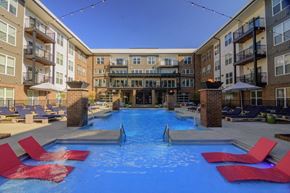 Columbus apartment for rent - a large swimming pool with red chairs in front of an apartment buildingat Taylor House Apartments, Columbus, Ohio