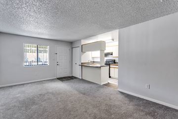 Titusville apartment for rent - the living room and kitchen of an apartment with white walls and carpet