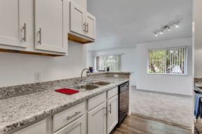Melbourne apartment for rent - a kitchen with white cabinets and granite counter tops and a sink