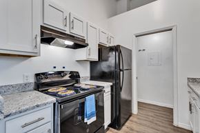 Melbourne apartment for rent - a kitchen with white cabinets and stainless steel appliances and a black refrigerator