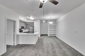 Ft Worth apartment for rent - A spacious, empty room with a ceiling fan and a staircase.