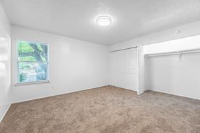 Ft. Worth apartment for rent - A room with a carpeted floor and a window showing a view of trees and a house.