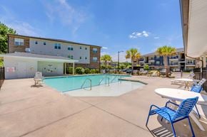 Savannah apartment for rent - A swimming pool with a blue chair and a white table in front of a building.