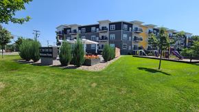 Mounds View apartment for rent - an apartment building with a green lawn and trees in front of it