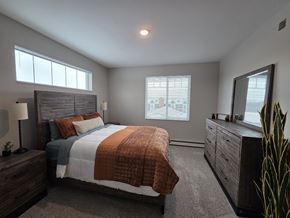 Annandale apartment for rent - A bedroom with a large bed, a nightstand with a lamp, and a dresser with a mirror.
