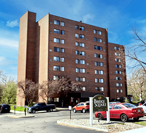 Anoka apartment for rent - A large brick building with a sign that says Bridge Square in front of it.