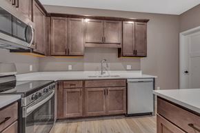 Little Falls apartment for rent - A kitchen with brown cabinets and a white dishwasher.