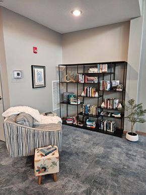 Alexandria apartment for rent - A room with a bookshelf, a chair, and a small tree.