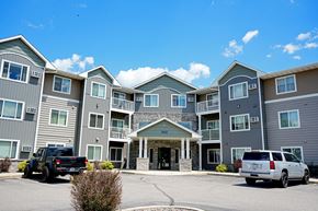 St Cloud apartment for rent - A large building with a grey and green exterior and a stone pillar in front.
