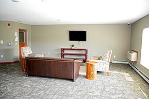 Gaylord apartment for rent - A living room with a brown couch, a chair, and a television.