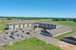 East Bethel apartment for rent - A parking lot with cars and a building in the background.