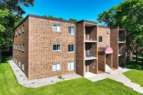 Sartell apartment for rent - A red brick building with a green lawn in front.