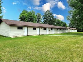 Twin Valley apartment for rent - A long white building with a brown roof sits in a grassy field.