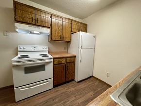 St Cloud apartment for rent - A kitchen with a white stove and refrigerator, wooden cabinets, and a sink.