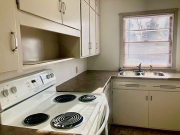 Morris apartment for rent - A white stove with four burners is in a kitchen with white cabinets.