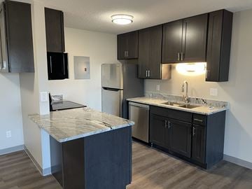 Isanti apartment for rent - A kitchen with black cabinets and a granite countertop.