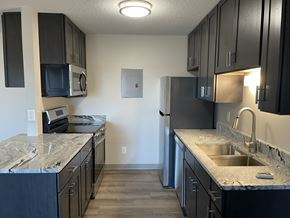 Isanti apartment for rent - A kitchen with black cabinets and granite countertops.