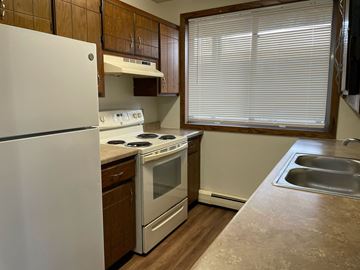St Cloud apartment for rent - A kitchen with a white refrigerator, white oven, and a window with blinds.